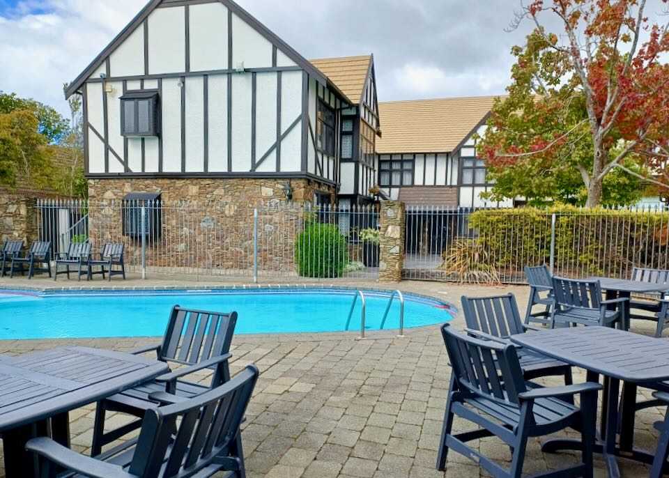 Black tables and chairs sit around a blue pool.