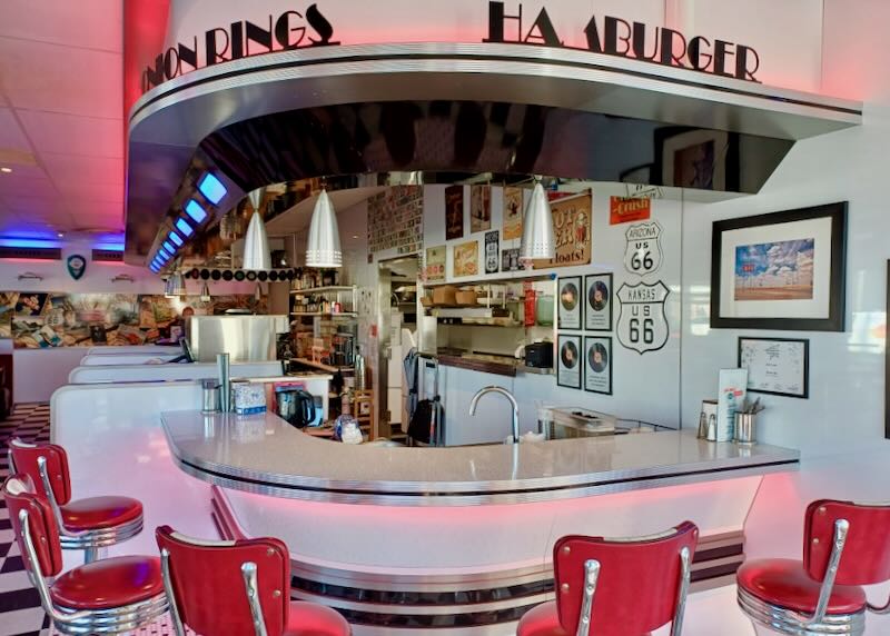 Red diner stools sit around a red lit counter.