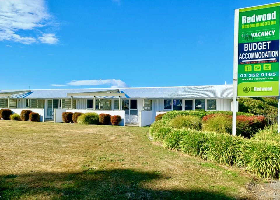 A motel sign reads, "Redwood Accommodation."