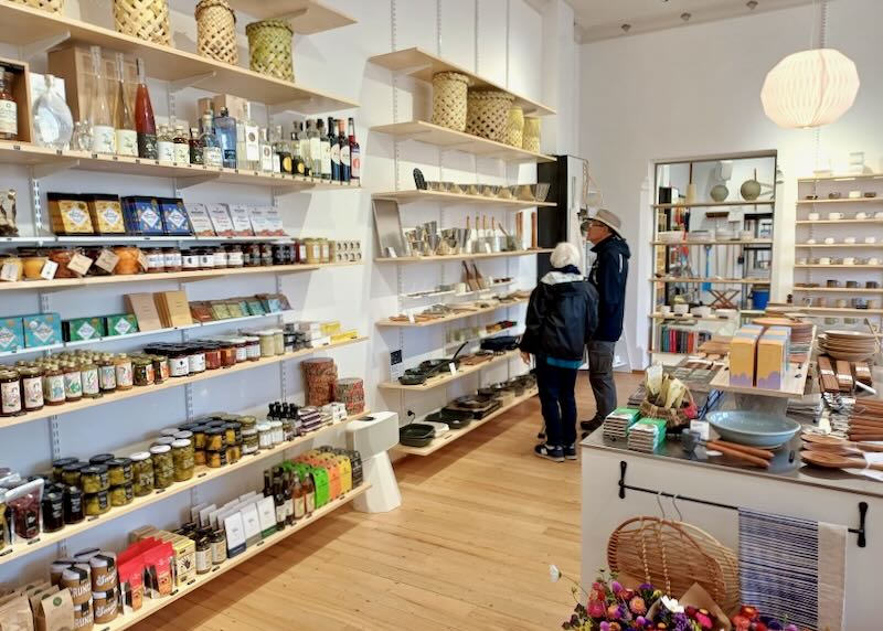 A couple look inside a shop at shelves of goods.