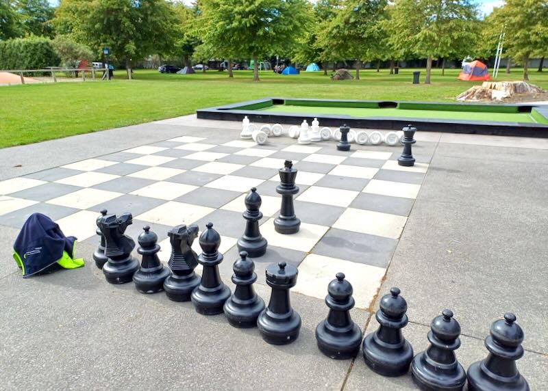 A large lawn chess game with black and white pieces.