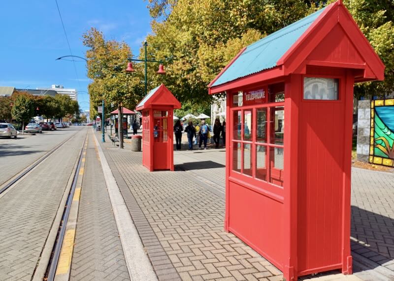 Red telephone rooms stand along a street.