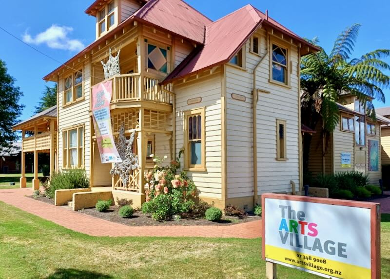 A yellow house with sculptures that looks like spider webs on the house.