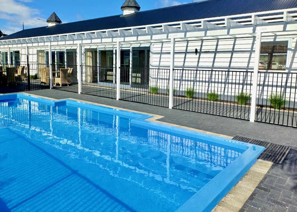 A blue pool sits next to a white motel.