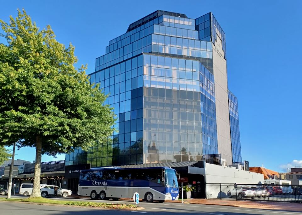 A large multi-level hotel with a glass exterior reflects the blue sky in its windows.