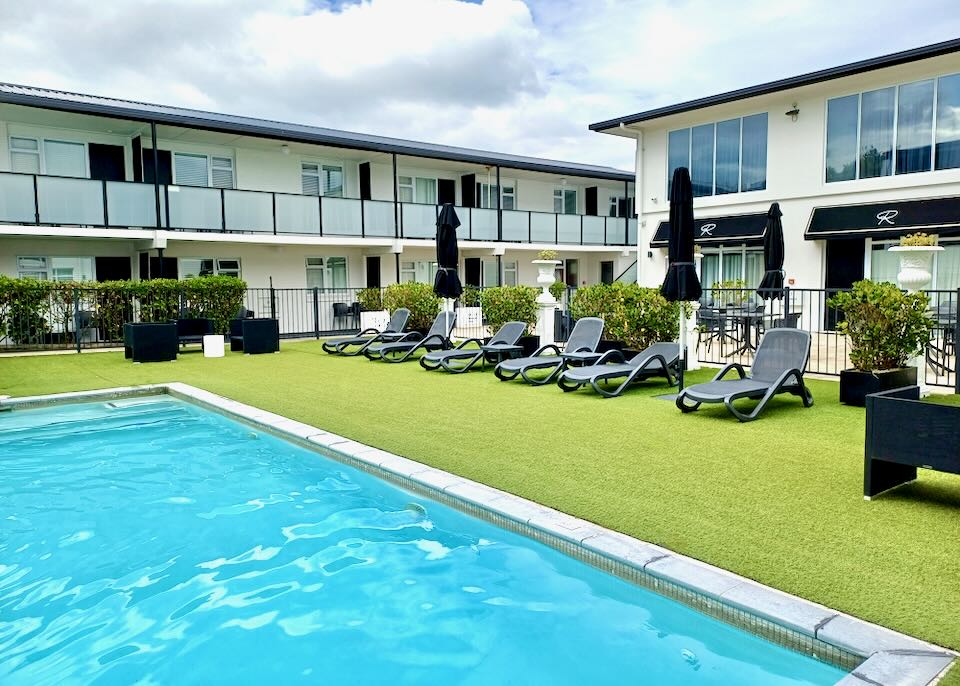 A light blue pool sits in the middle of a courtyard inside a motel.