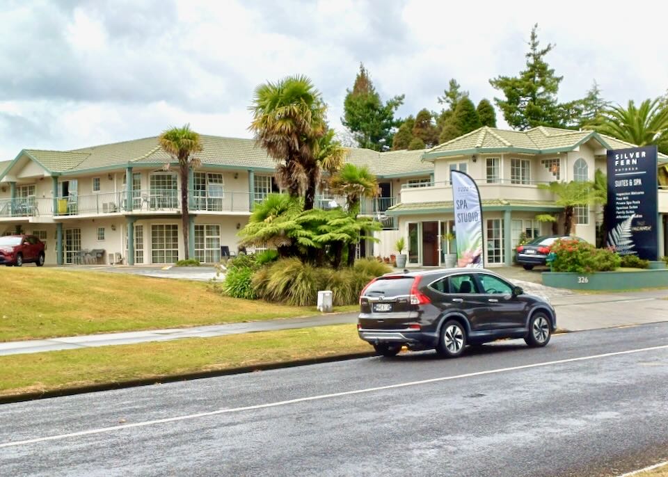 A parked car sits in front of a motel.