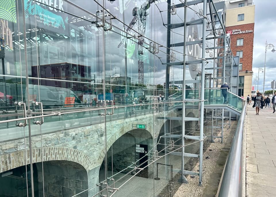 View down a sidewalk past a glass building front to a brick hotel