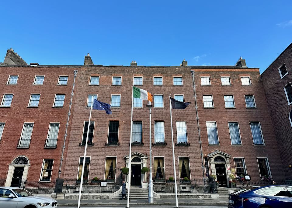 Exterior of a red brick hotel building, with Irish flags flying in front