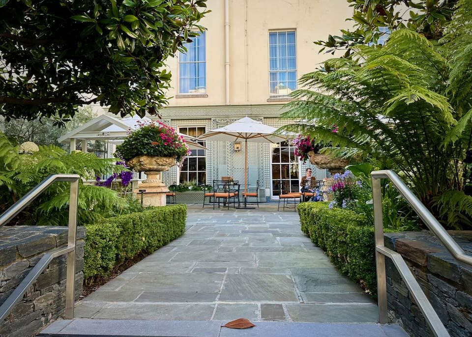 View up a stone path to a garden courtyard with cafe tables