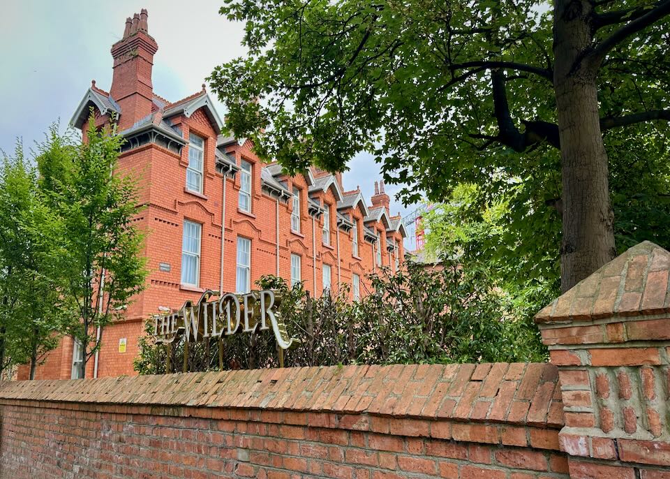 View looking over a brick fence to a red brick hotel building