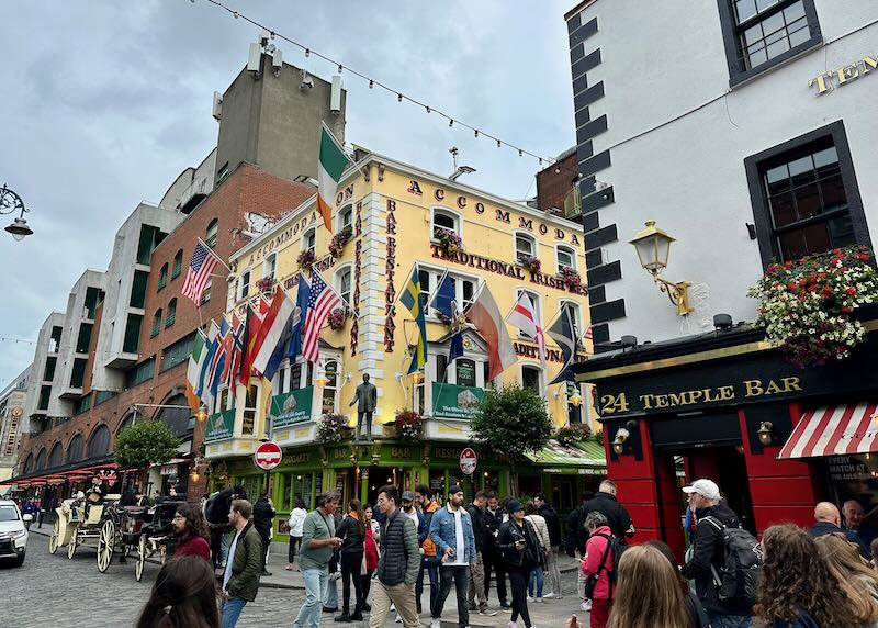 Crowds on the streets of the Temple Bar neighborhood in Dublin, amid colorful buidings strewn with flowers and flags