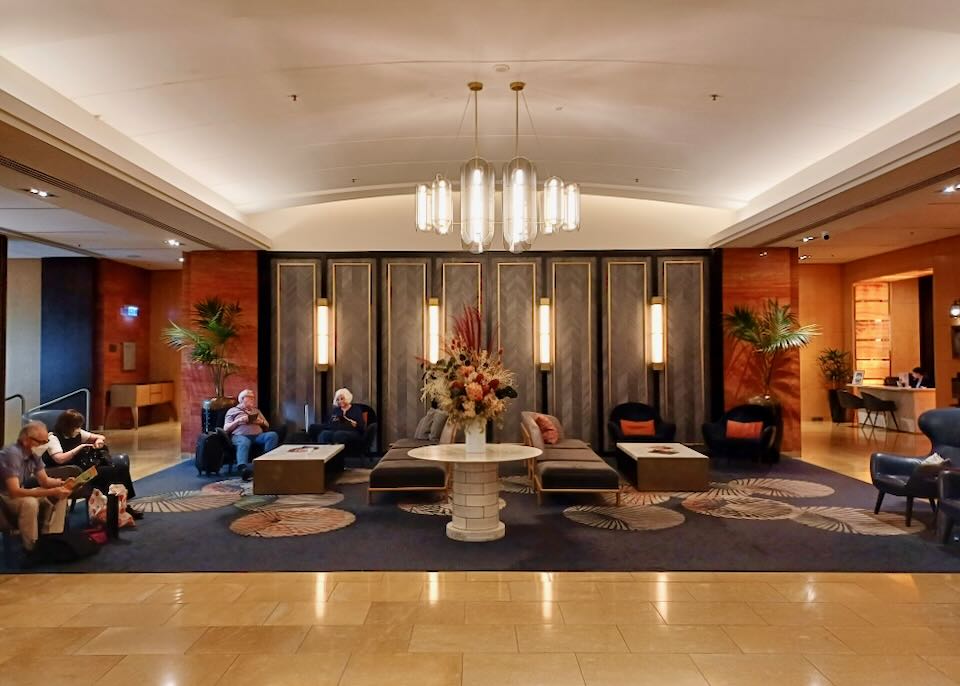 Guest sit in plush velvet chairs in a hotel lobby.