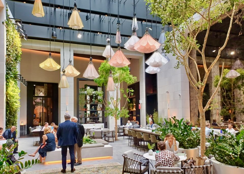 People sit at tables in a airy restaurant with mechanical flowers overhead that drop and open.