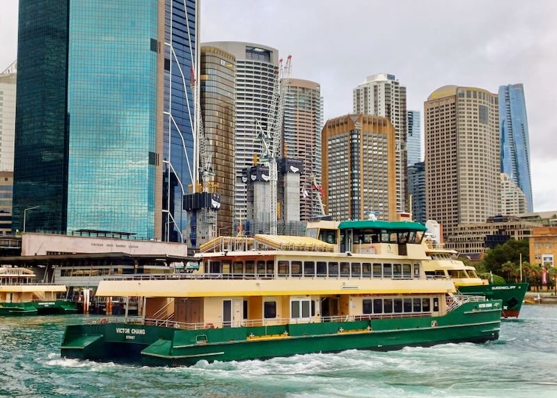 A green and yellow ferry maneuvers into position on the cities waterfront.