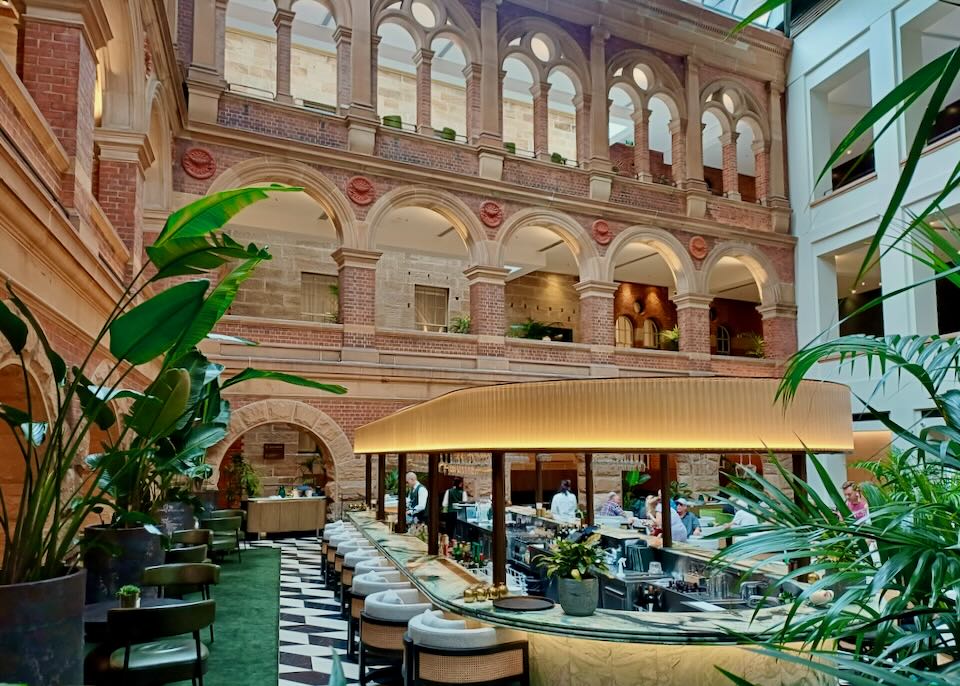 A bar sits in the center of a lobby with orange brick arched walkways piled three levels up.