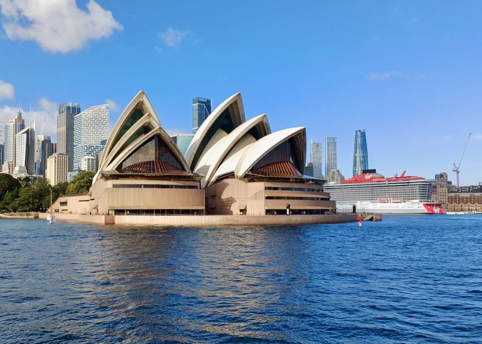 A building with points and petals like a flower sits on the water.