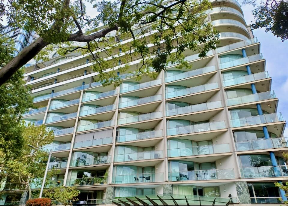 A multi-level hotel has balconies with glass railings to allow for a view of the harbor.