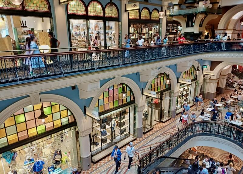 Shoppers walk the many levels of a historic hall filled with shops.