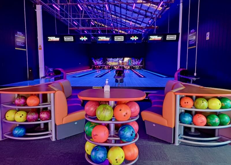 Neon bowling balls glow in the dark and light bowling alley.