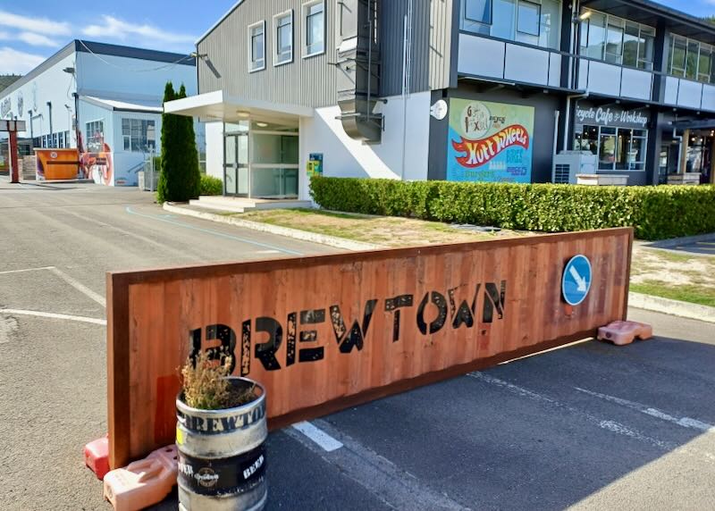 An orange metal sign with black letters says, "Brewtown."