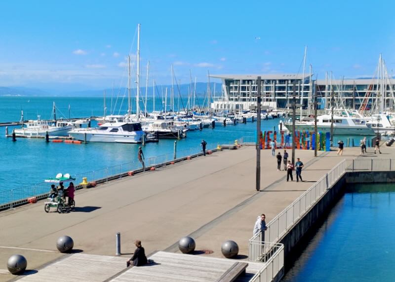 A large pier with tourists looking over the harbor.