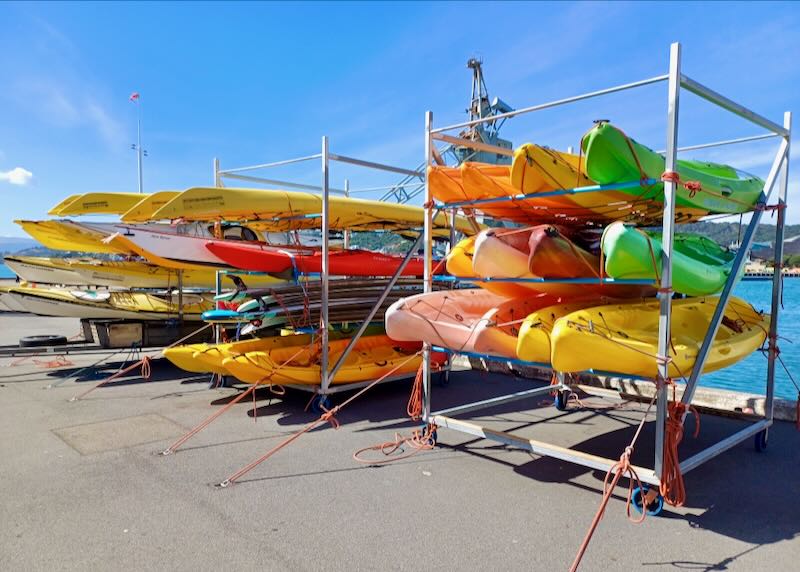 Three racks of kayaks sit on the edge of a pier.