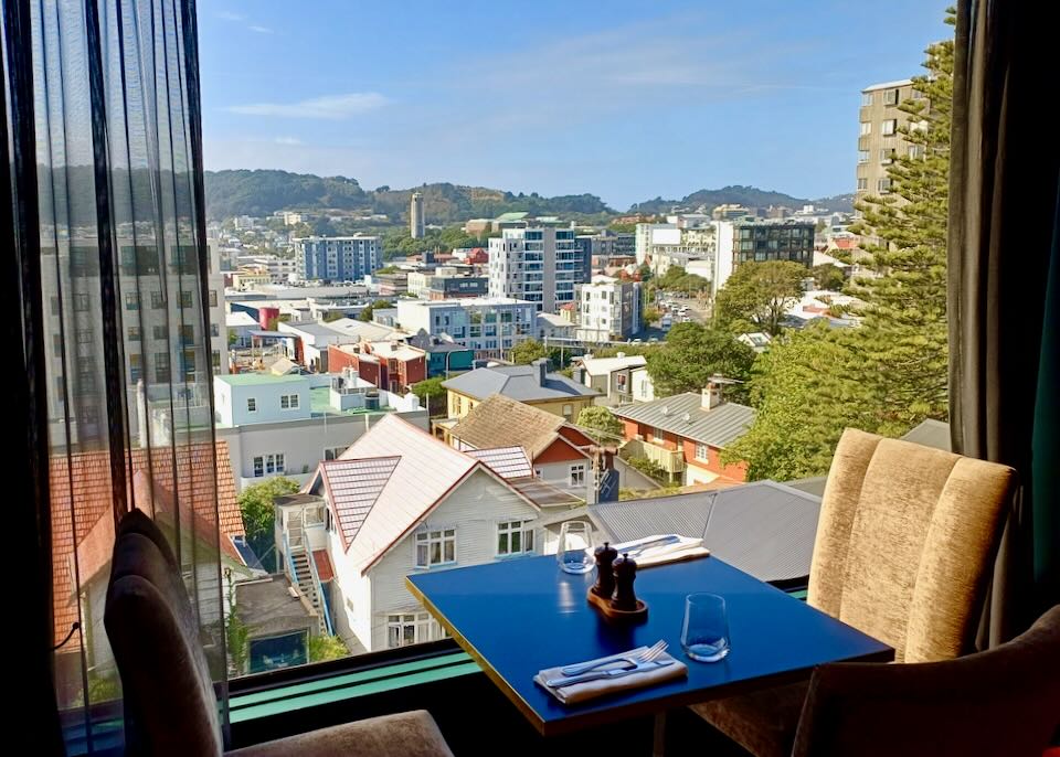 A large window by a table in a cafe shows views of the city from a few stories up.