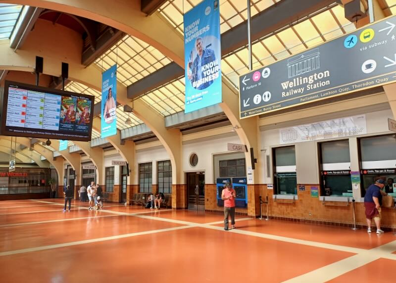 A man walks through a high-ceiling railway station.