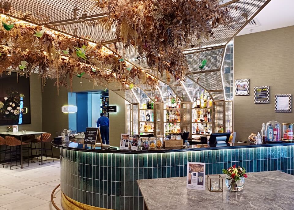 A dark green tile lines a bar where above a wire mesh holds hundreds of dried flowers.