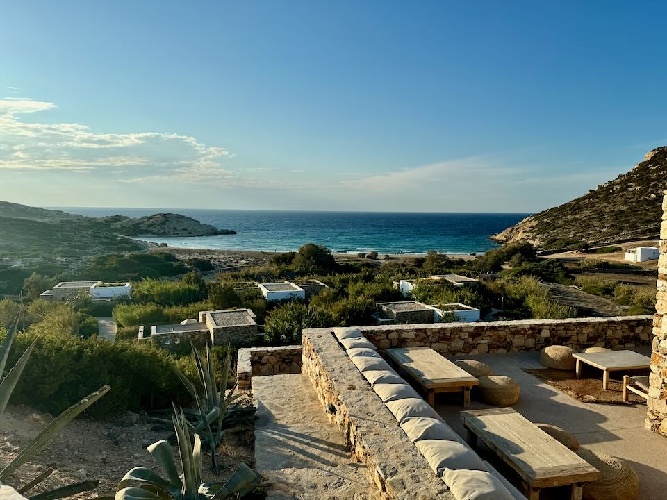 View looking over a luxury hotel complex in a Greek island hillside to the sea at sunset.