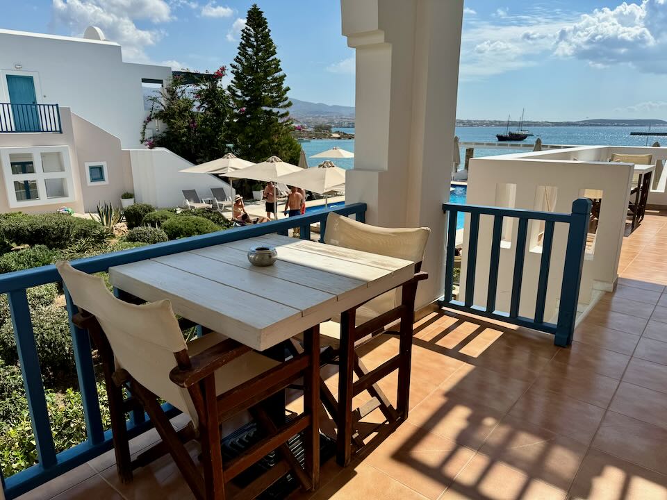 View from a hotel balcony across a pool terrace to the sea.