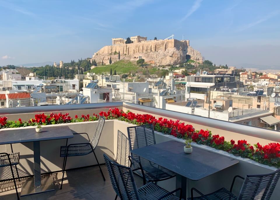 View of the Athens Acropolis from a rooftop deck set with tables and chairs