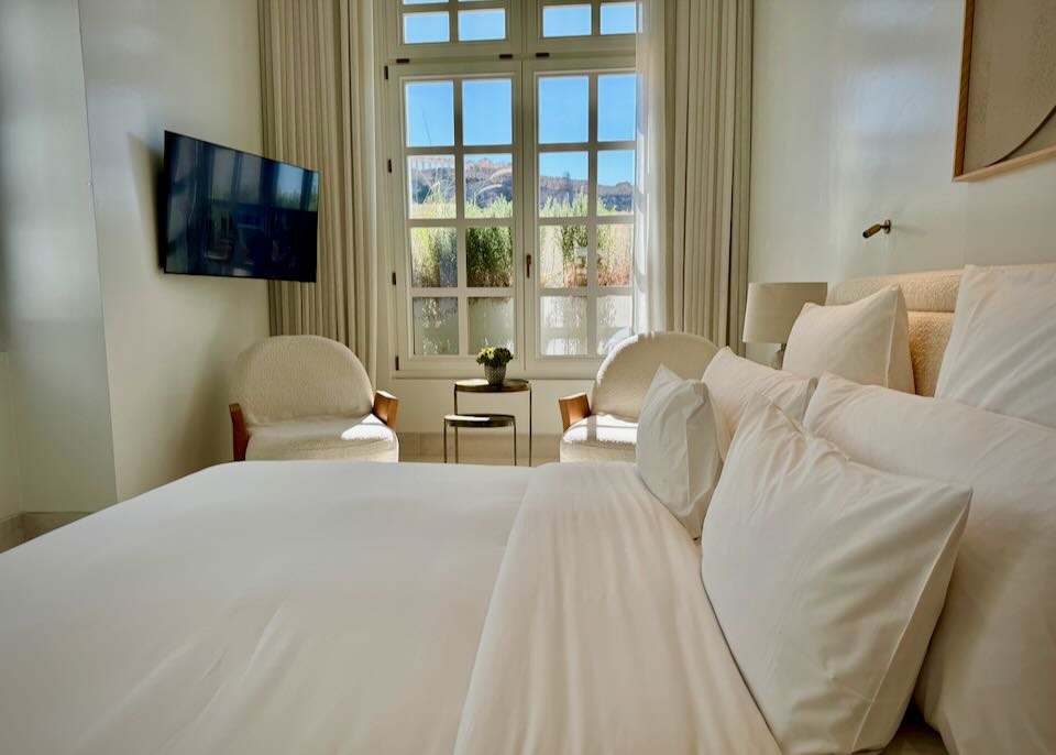 Hotel room with plush bedding and view of the Acropolis in Athens.