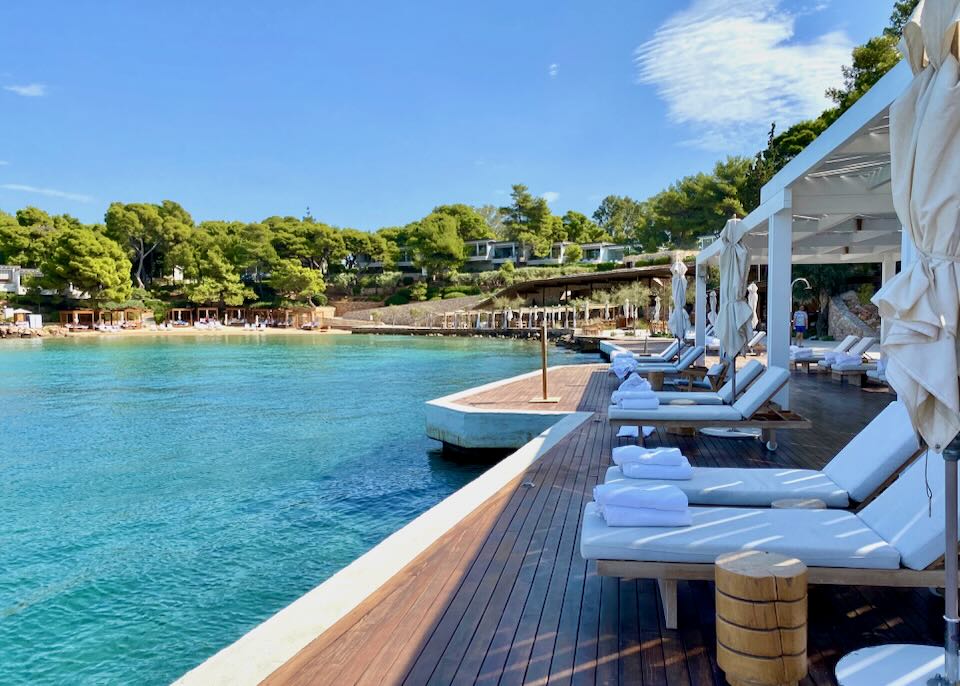 Hotel sun beds set over a pool next to a beach on a sunny day