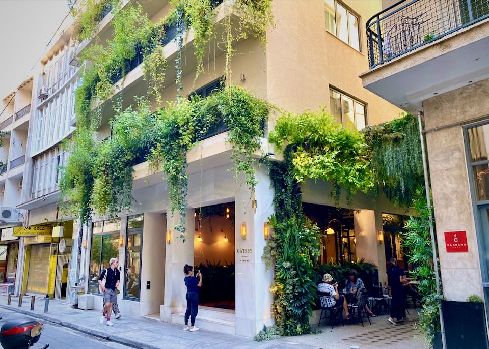 Exterior of a vine-covered hotel, with a pedestrian taking a photo in front.