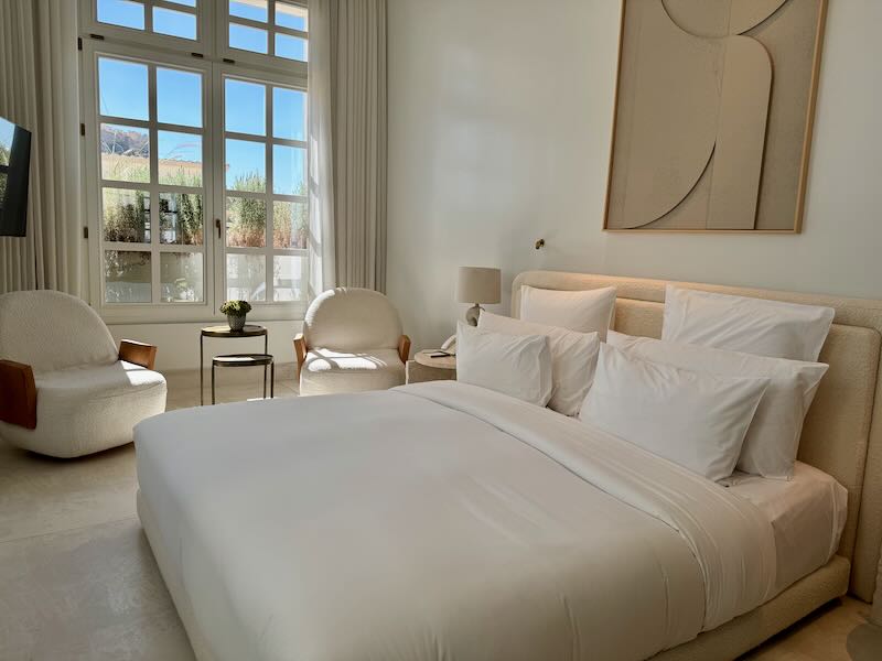 Hotel room with puffy white linens and large window with Acropolis view