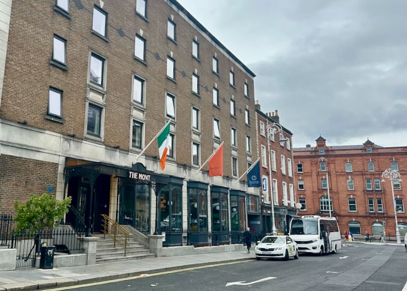 View looking down the street past a luxury hotel with Irish flag flying.