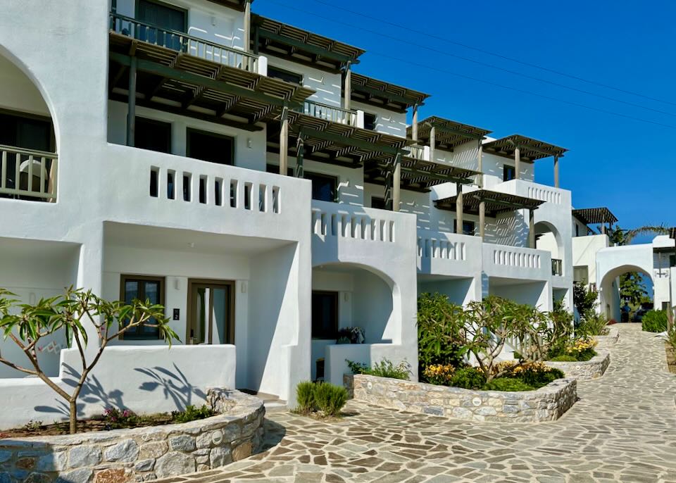 White hotel suites in a row, with balconies covered by wooden trellising.