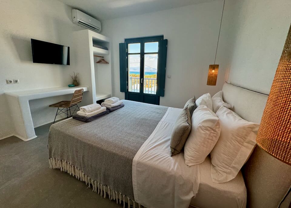 Comfortable looking hotel bed with balcony looking out to the sea.