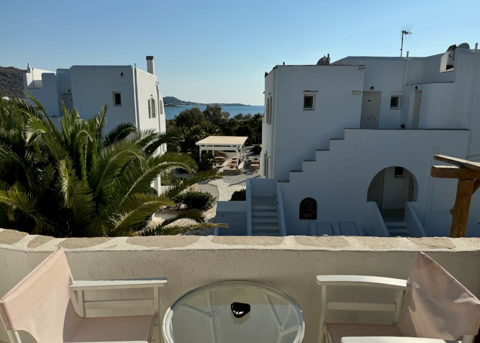 View past boxy, white Cycladic hotel buildings to the sea. 