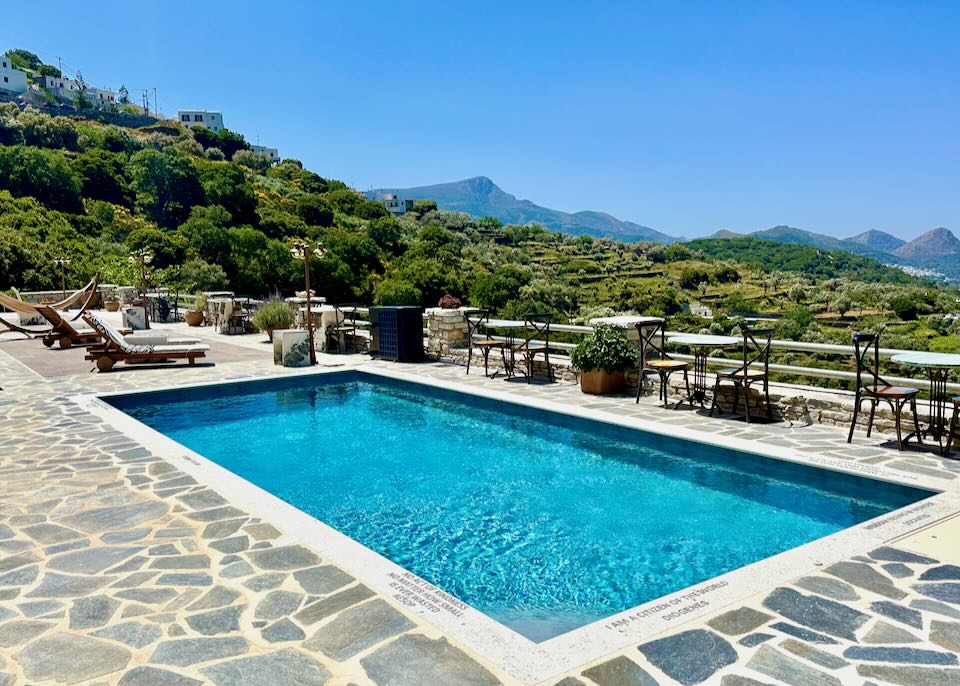 Stone terrace with sparkling blue pool overlooking a forested mountainside.