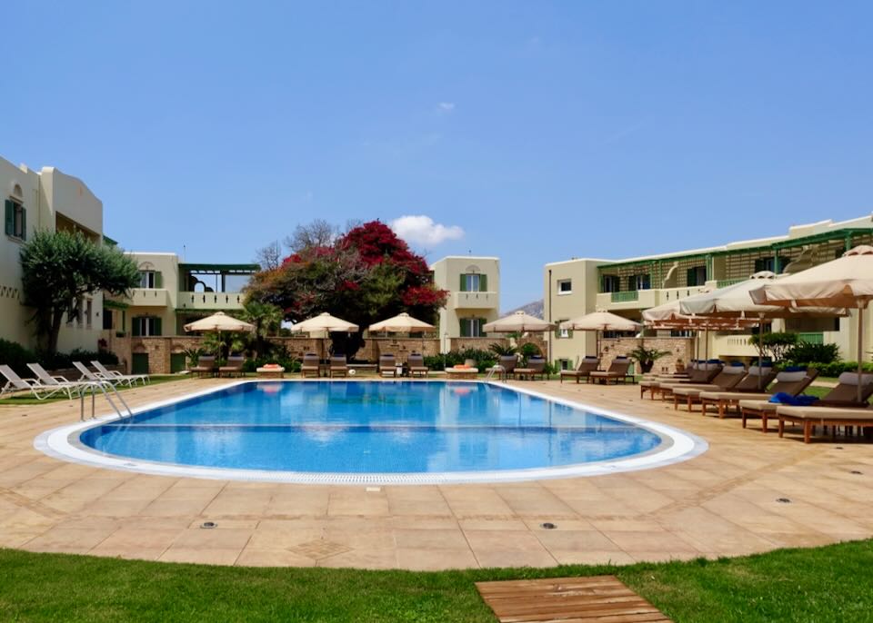 View of a hotel pool deck, ringed with sun loungers.