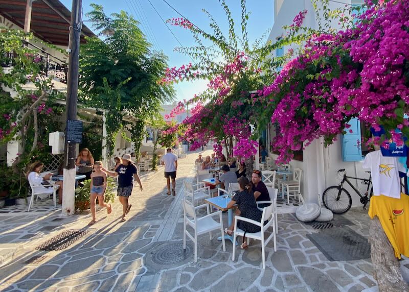 People walk past souvenir shops and cafes in the narrow pedestrian lanes of Parikia Town.