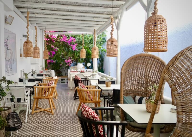 Rattan chairs at cafe tables in a covered hotel veranda