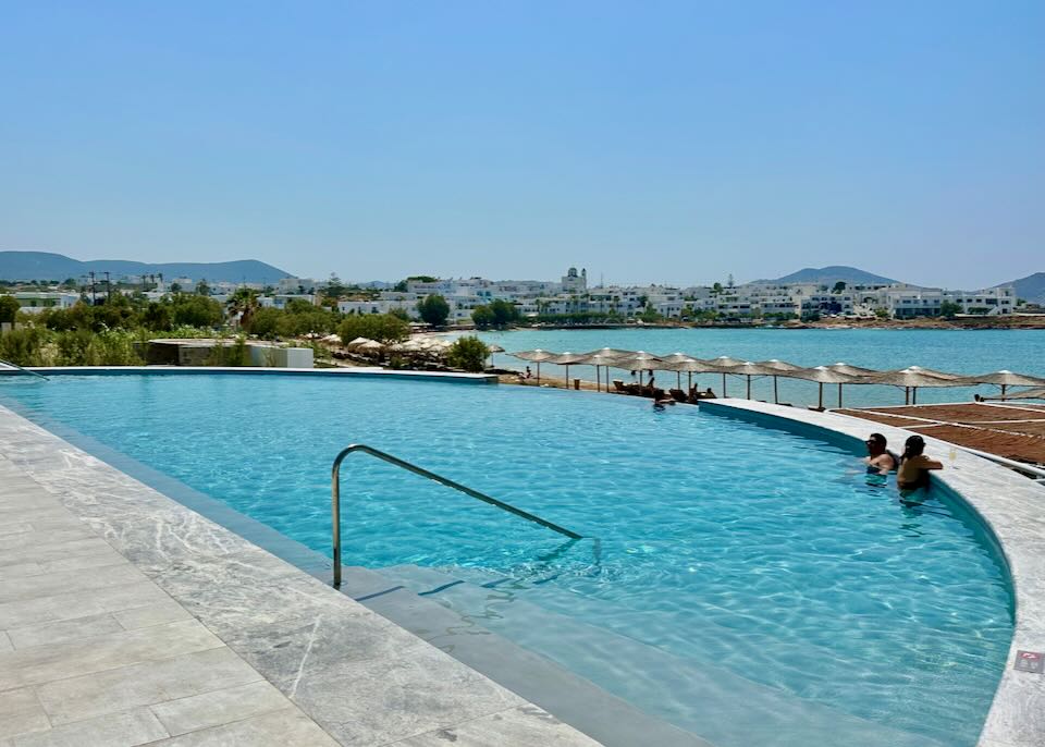 A person looks over the edge of an infinity swimming pool to the blue sea.