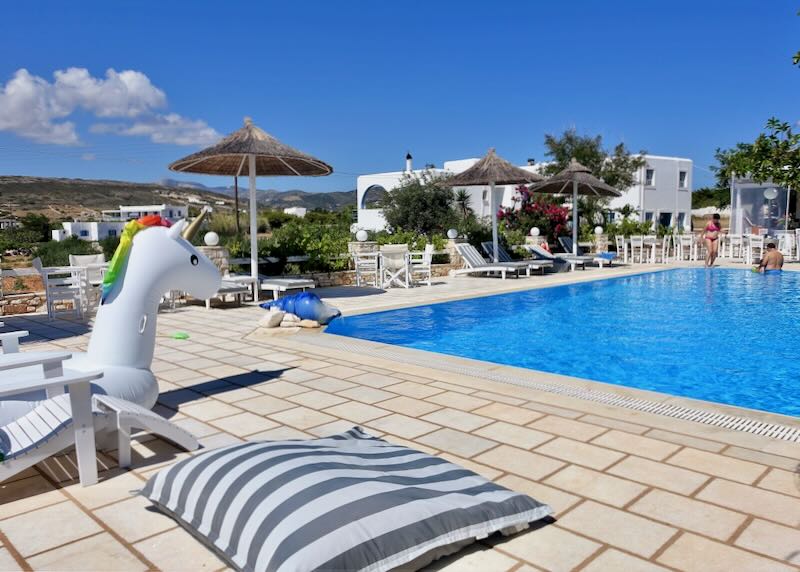 Hotel swimming pool surrounded by sun loungers and toys, such as a large inflatable unicorn