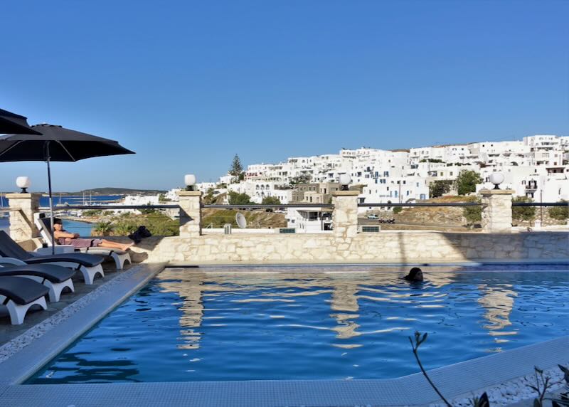 The white boxy buildings of Naoussa, Paros, seen from behind the waters of a swimming pool