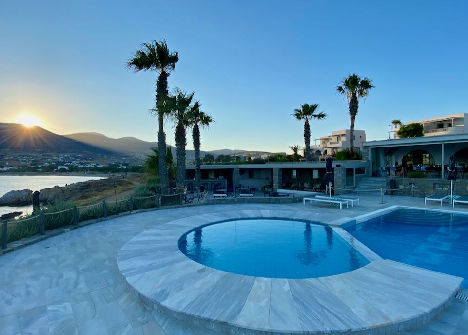 Hotel swimming pool and hot tub at sunset.