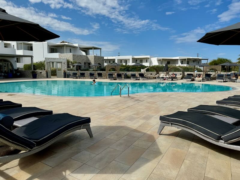 A woman and a child swim in a hotel swimming pool ringed by black umbrellas and sun loungers